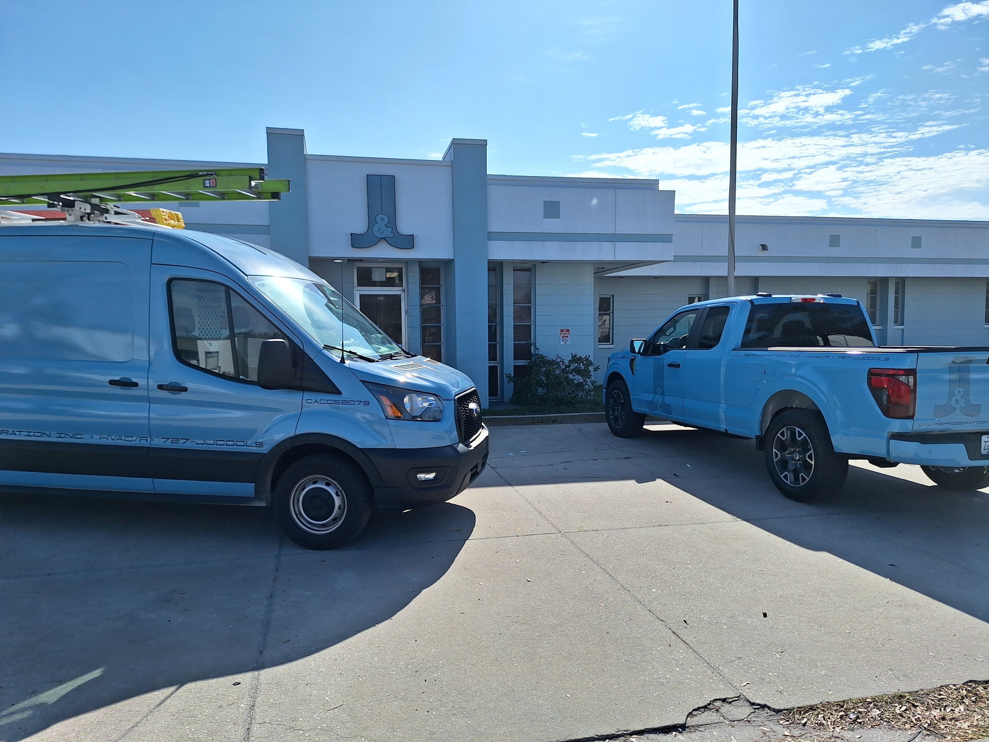 The front of J&J Refrigeration Inc. building with a van and truck.