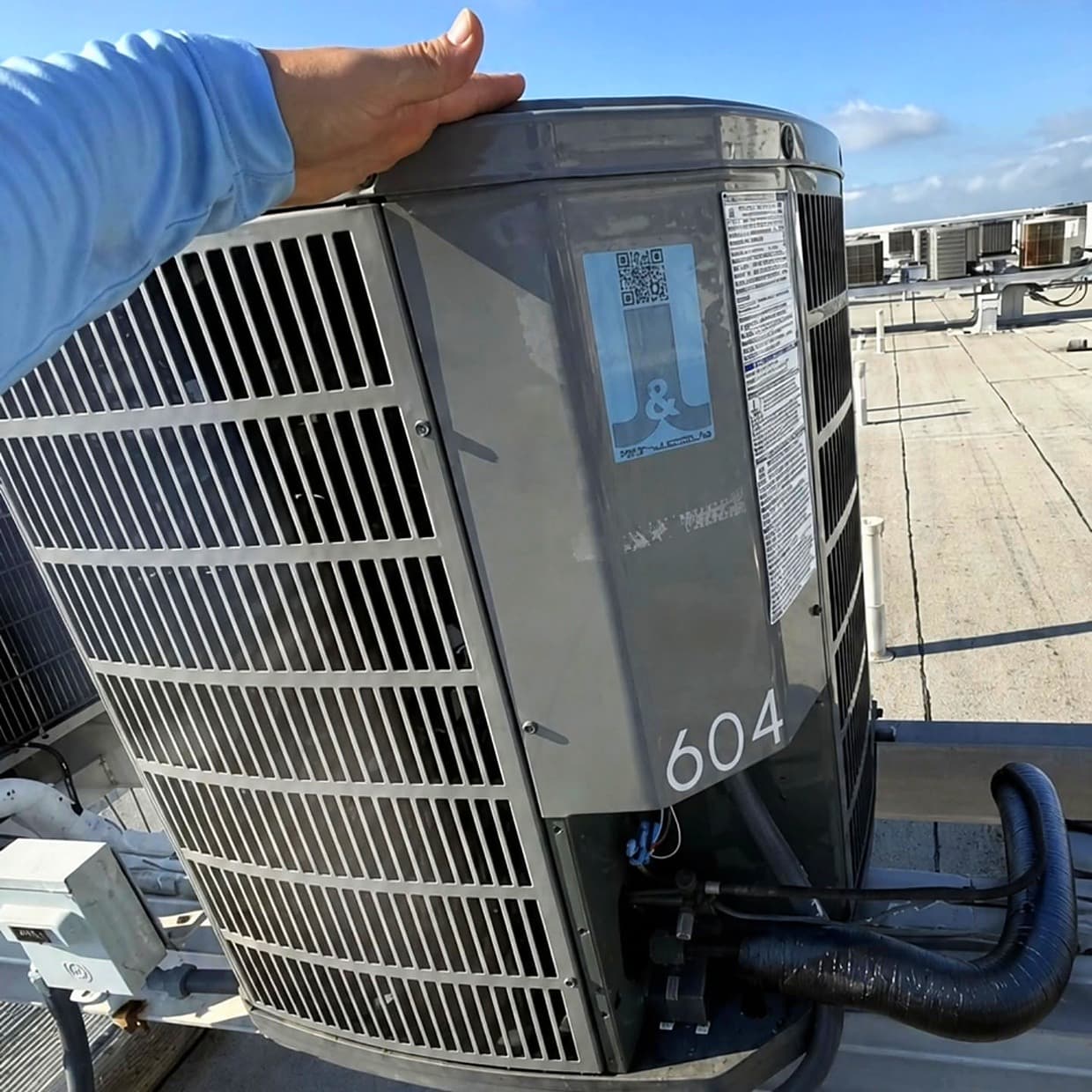 A rooftop condensing unit marked 604, carrying a J&J Refrigeration service sticker
