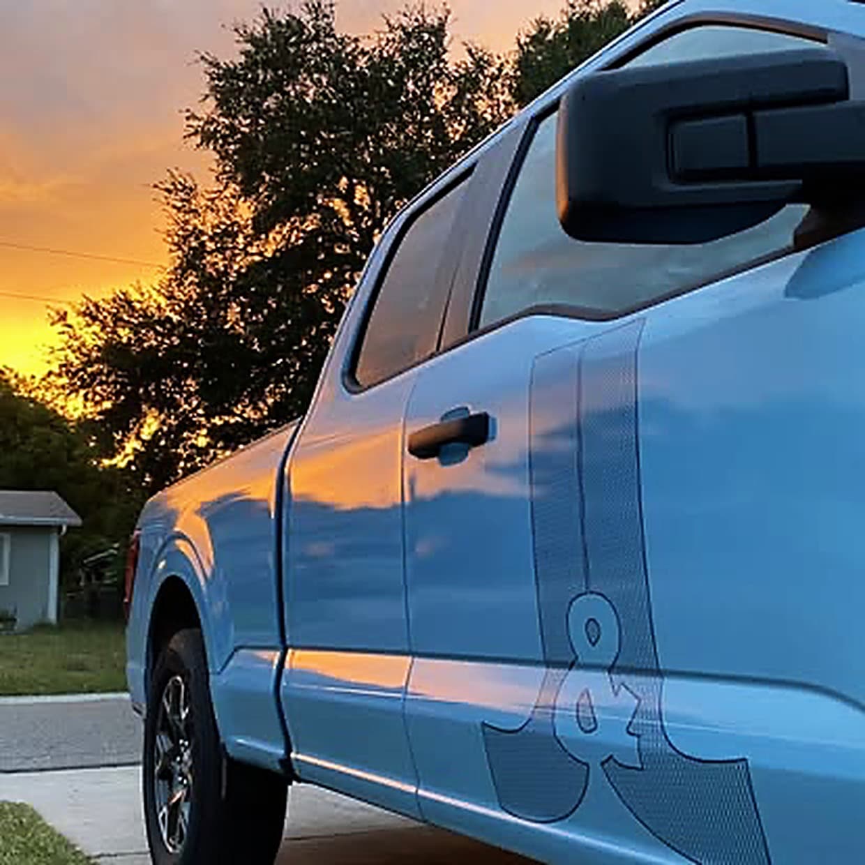 A J&J Refrigeration pickup parked on a Tampa Bay street at sunset, the J&J mark along its side