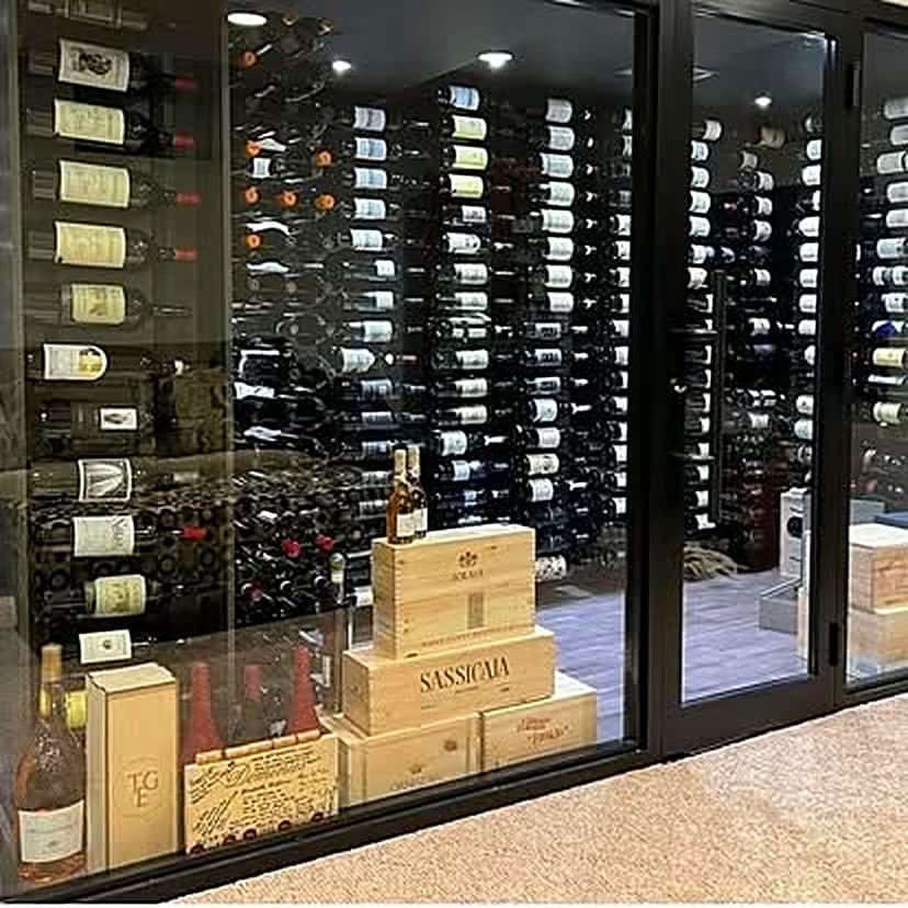 A large glass-walled wine cellar filled floor to ceiling with bottles and wooden cases
