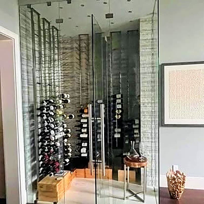 A glass-enclosed wine cellar with black steel racking in a light, modern room