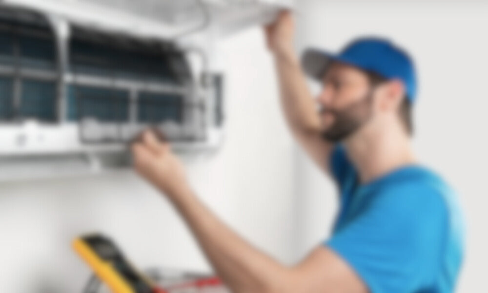 A HVAC Tech working on an indoor mini-split unit blurred.