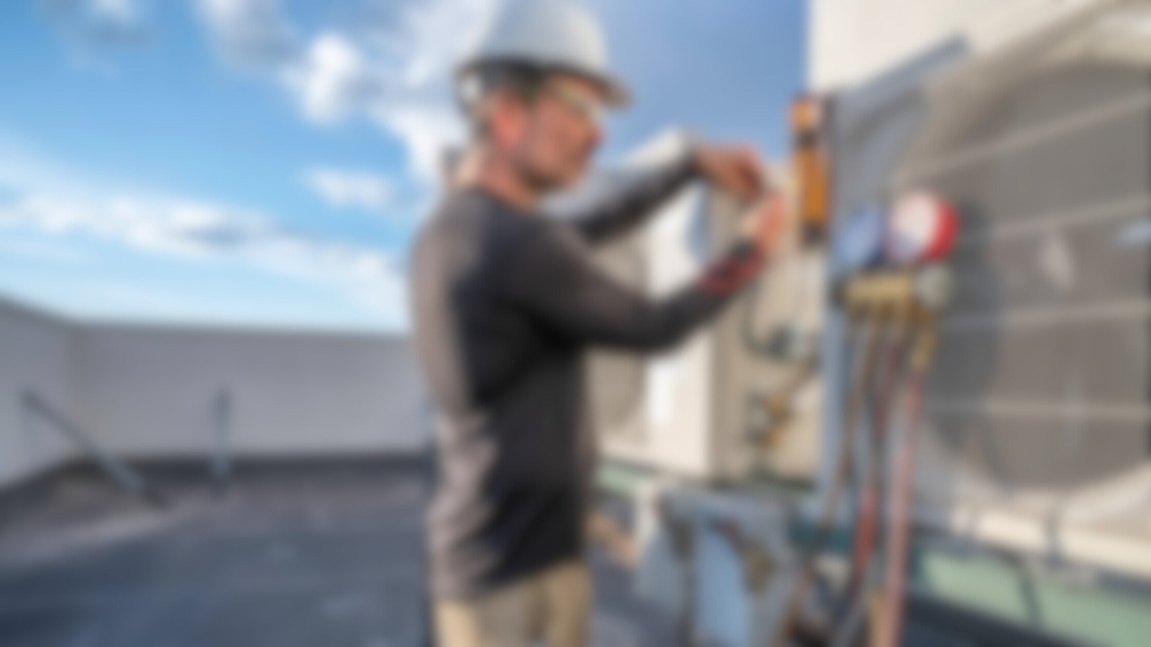 A man on a building fixing a outdoor air unit blurred.